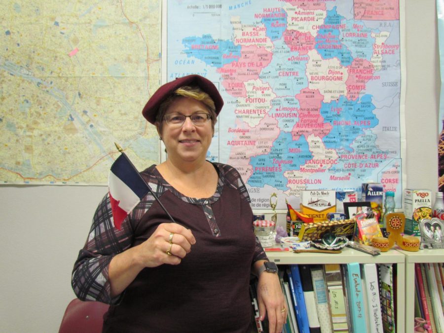 Mrs. Stanley poses with her mini French flag in front of her maps.