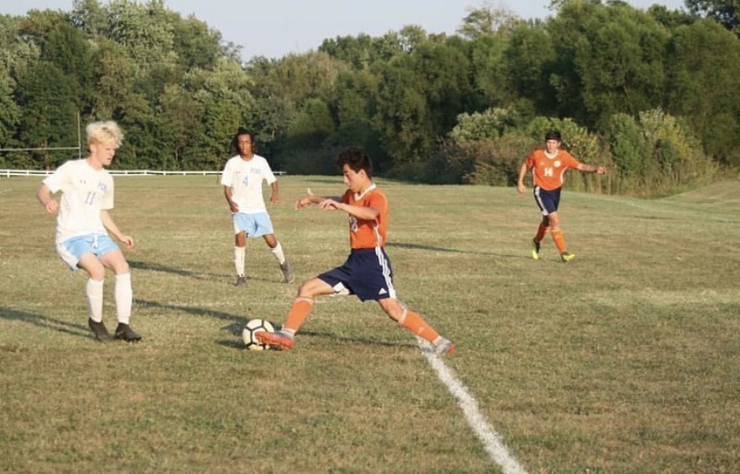 Jesus Mendez (10) runs toward the ball, passing a defending player. 