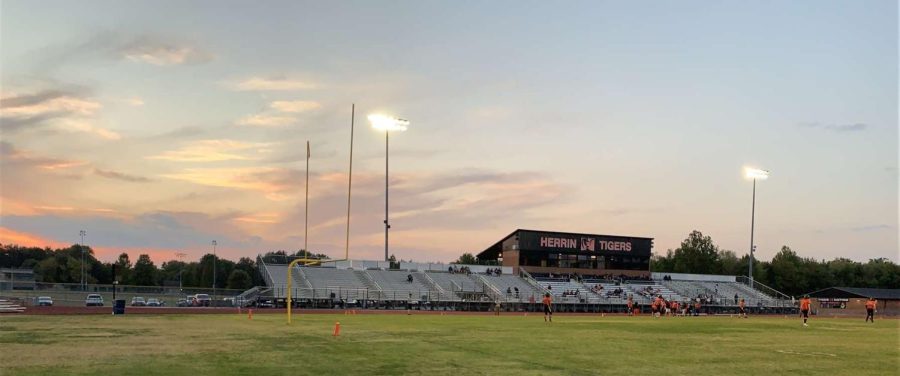 The Tiger football field stands in the foreground of a gorgeous sunset.