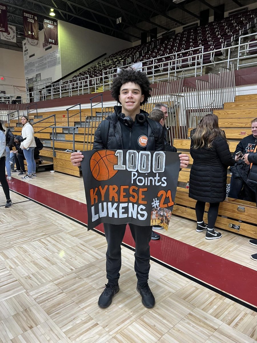 Kyrese Lukens (11) proudly holds a sign that his mother, Kaci Lukens prepared for him in anticipation of his 1000th point. Kyrese accomplished this at the Benton Invitational Tournament against the Pinckneyville Panthers.