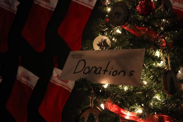 A traditional Christmas set-up, featuring a Christmas tree and stockings, as well as a donations envelope for charity.