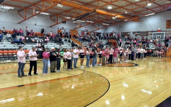 The 2026 Rose Walk participants line up on the gym floor as the audience applauds the cancer survivors